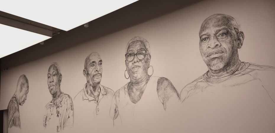 Five portraits of three men and two women drawn on a wall.